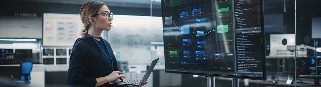 A woman looking at a large screen of data